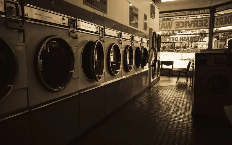 Sepia-toned image of a laundromat interior showcasing a row of classic washing machines.