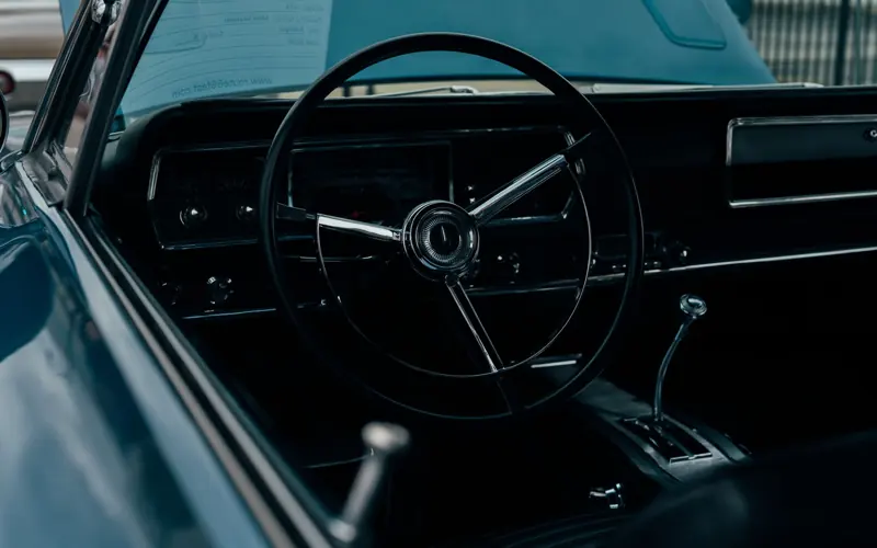Vintage car interior featuring a classic steering wheel and dashboard in moody lighting.