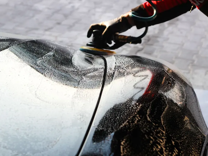 Close-up of a car being polished by hand, showcasing professional detailing and maintenance.