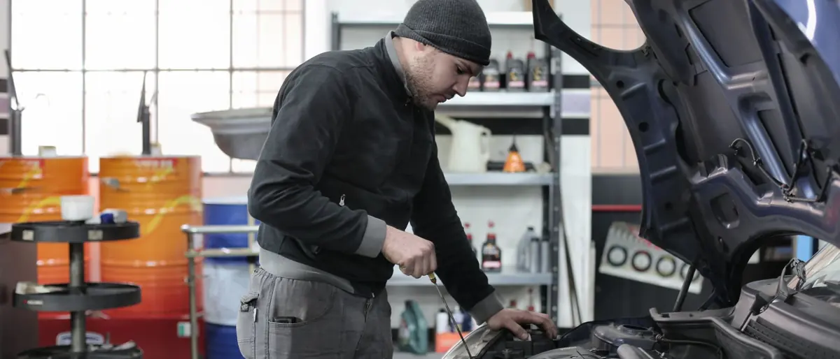 Mechanic checking a car engine in a garage, ensuring quality maintenance and repair.