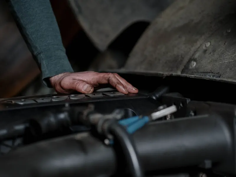 Crop unrecognizable male technician with dirty hands checking motor of vehicle in repairing workshop