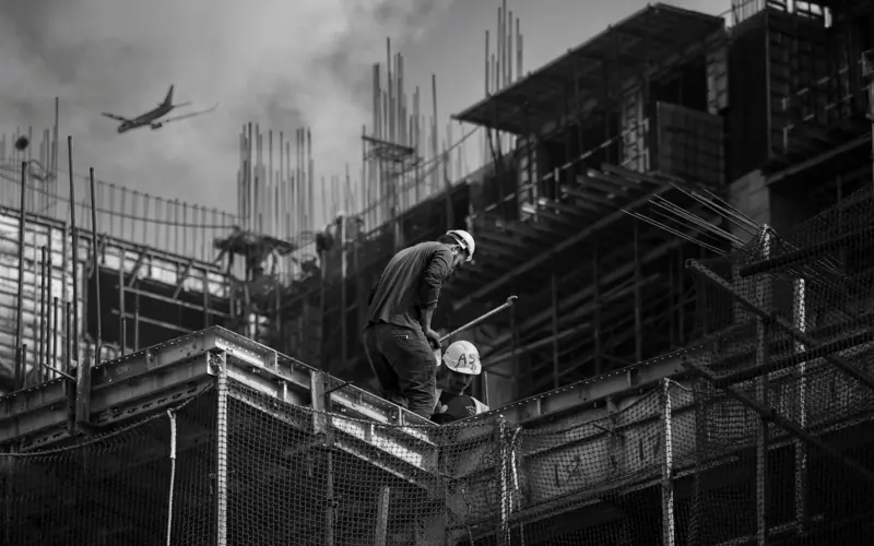 Black and white photo showing construction workers on an urban building site.