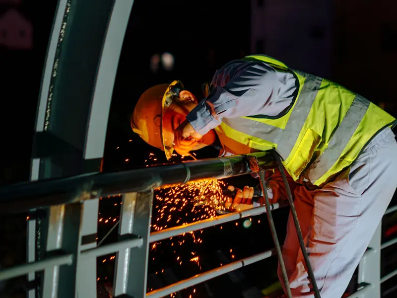 Night scene of a construction worker welding in Ho Chi Minh City, showcasing sparks and urban work atmosphere.
