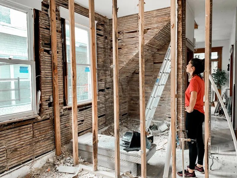 Side view of full body of woman in casual clothes standing in room with unfinished interior during maintenance