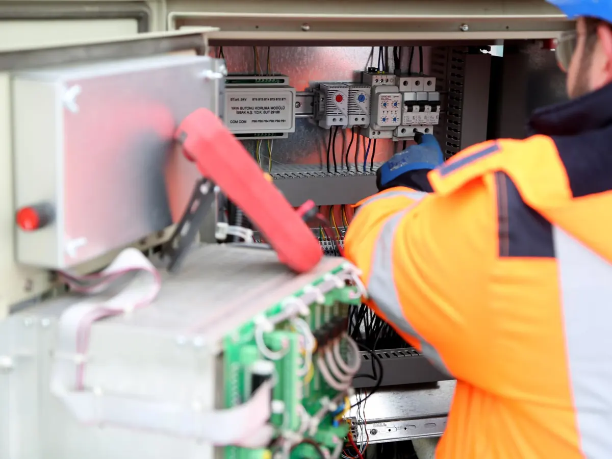 Professional engineer inspecting industrial electrical circuit board, ensuring safety standards.