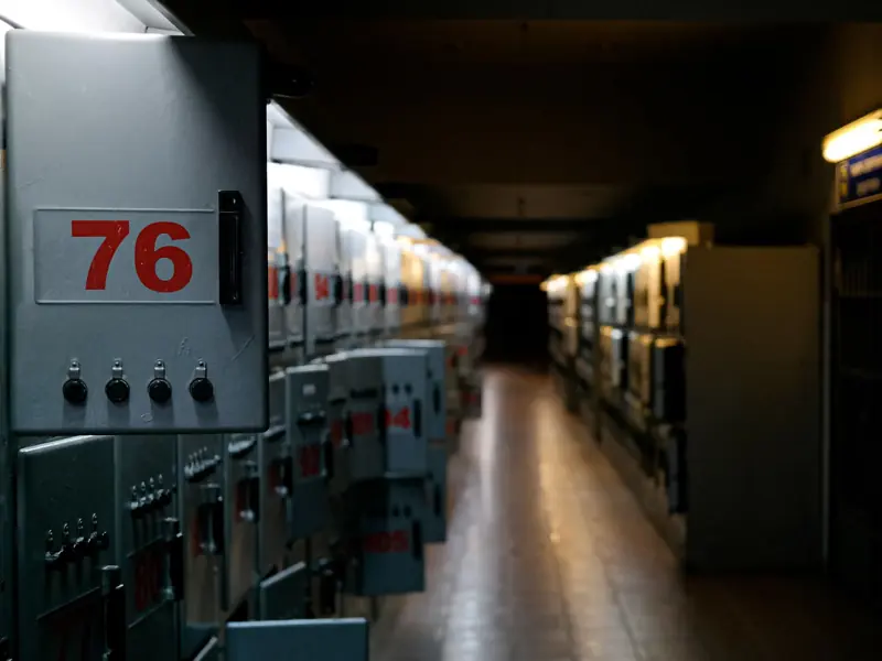 A moody shot of an industrial control room with labeled fuse boxes in dim lighting.