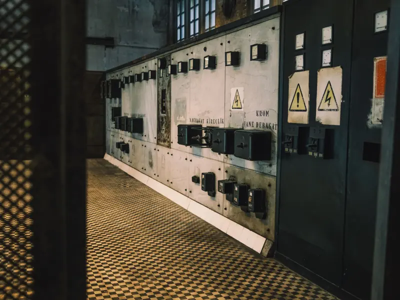 Vintage industrial control panel with warning signs in a dimly lit room, creating a moody atmosphere.