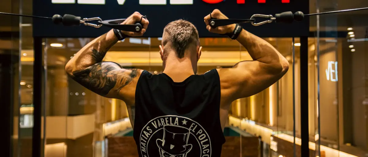 Back view of a muscular man working out in a modern gym, focusing on strength and fitness.