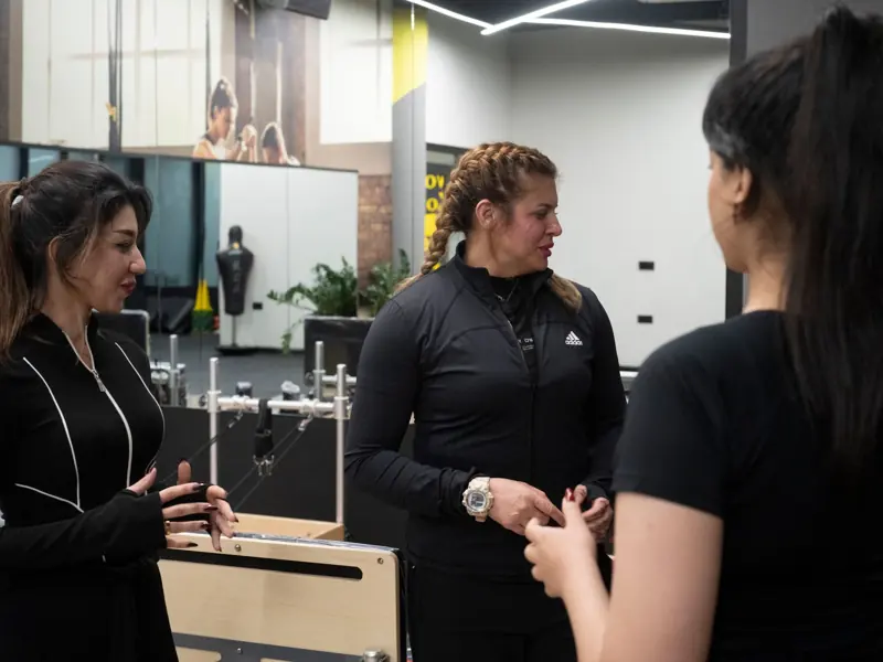 Three women in a modern gym having a conversation. Fitness and wellness theme.