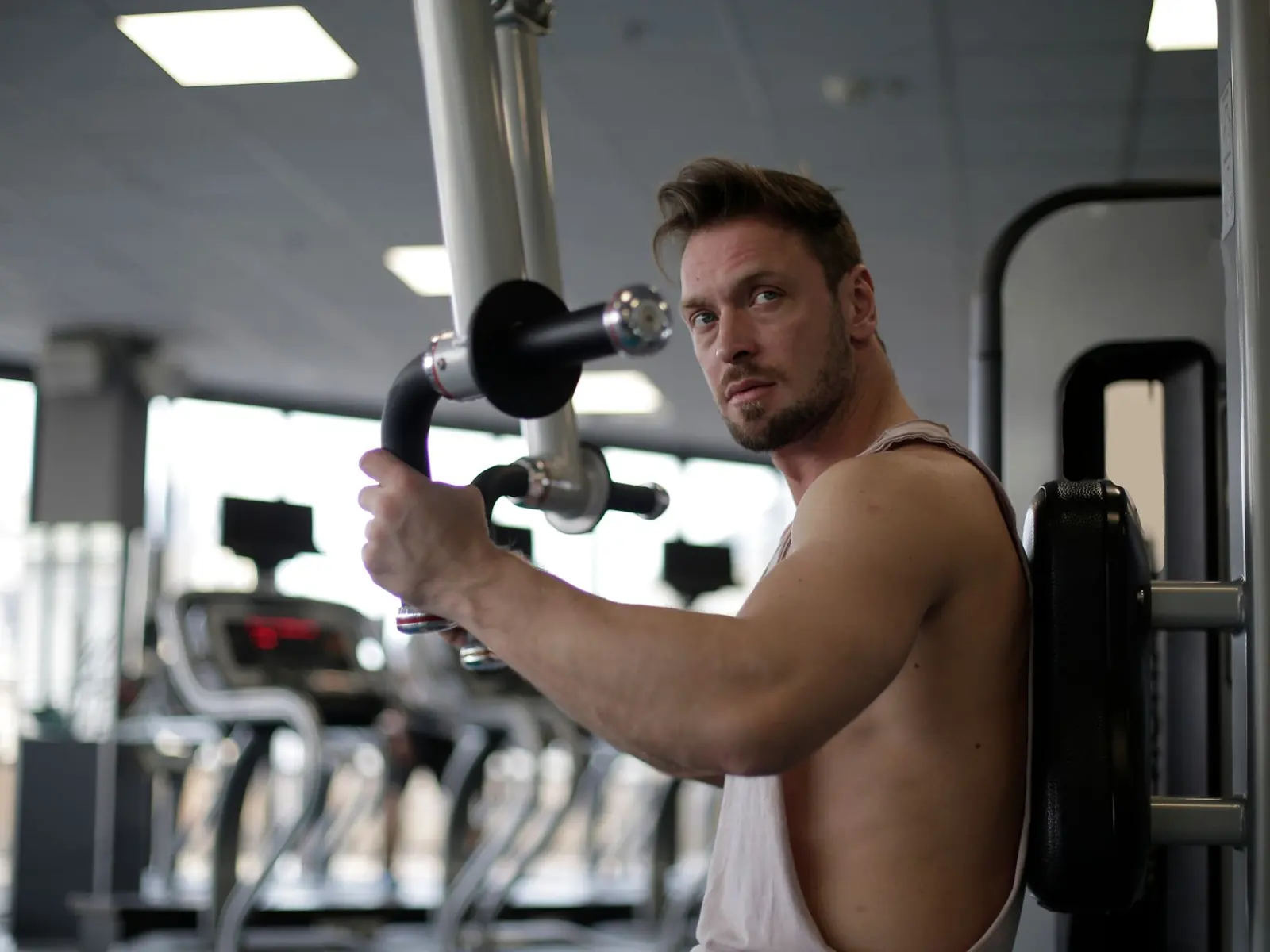 Focused man working out in a gym, showcasing biceps and determination.