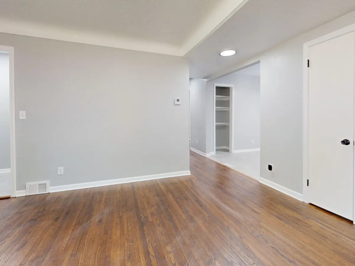 Bright empty room with wooden floor, perfect for real estate listings.