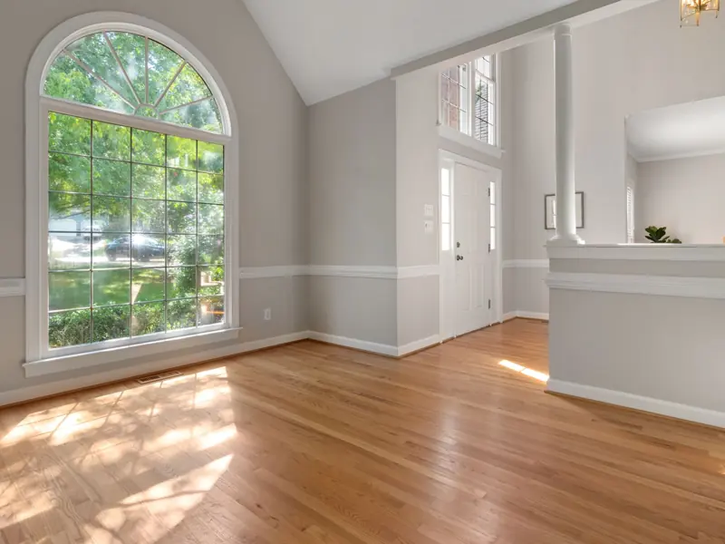 Bright living room with large window and hardwood floors, perfect for residential spaces.