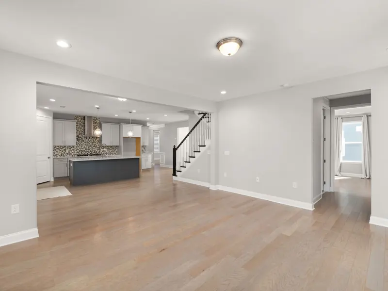 Spacious open-concept living room with hardwood floors and modern kitchen design.