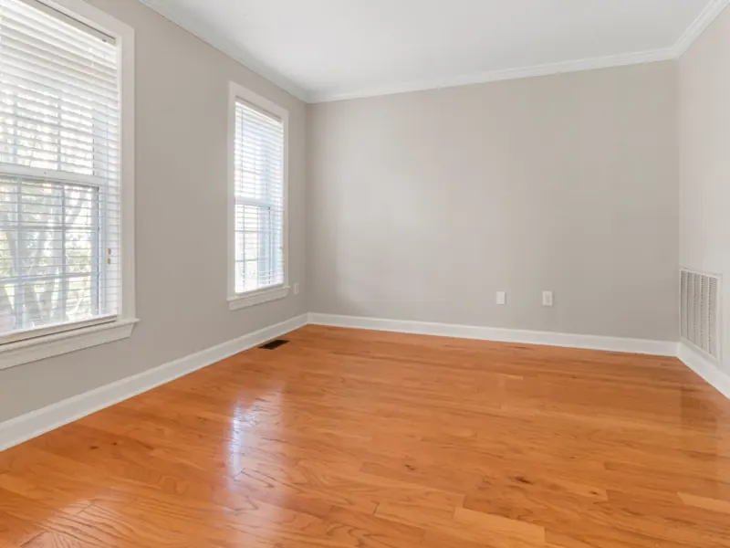 Spacious empty room with natural light, hardwood floors, and neutral walls.