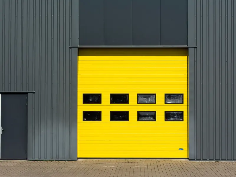 A sleek industrial structure featuring a vibrant yellow garage door for architectural interest.