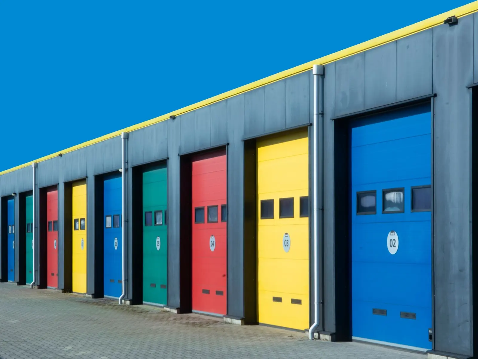 Vibrant row of industrial garage doors in blue, red, yellow, and green, perfect for commercial use.