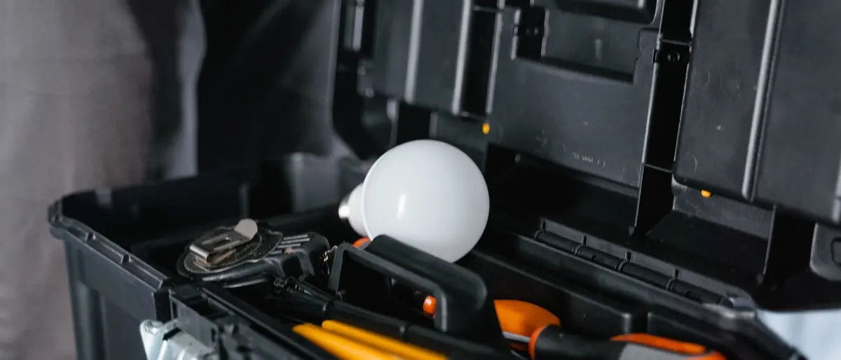 Open toolbox containing various tools and a light bulb.