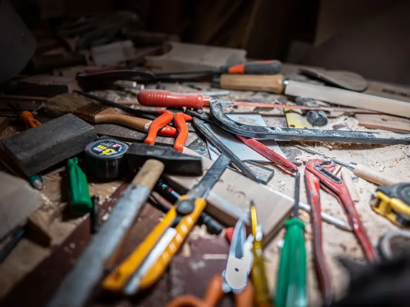 Close-up of a cluttered workbench with various carpentry tools and equipment.