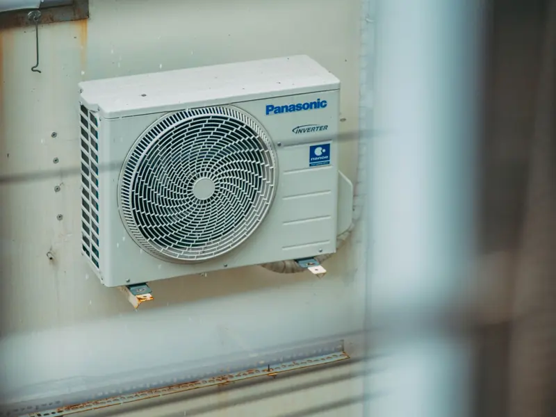 Air conditioner unit mounted outdoors on a building wall, showcasing modern HVAC technology.