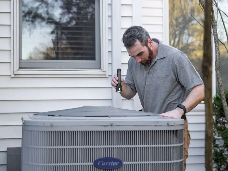 A technician inspects an outdoor HVAC unit for maintenance.