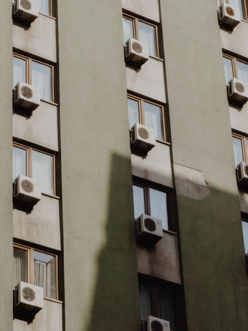 Facade of a city apartment building equipped with air conditioners on each window.
