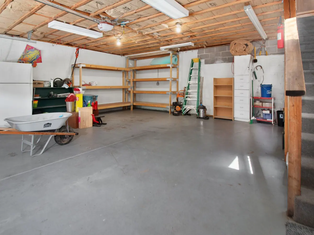 Spacious garage interior with storage shelves, tools, and a wheelbarrow, ideal for home organization.