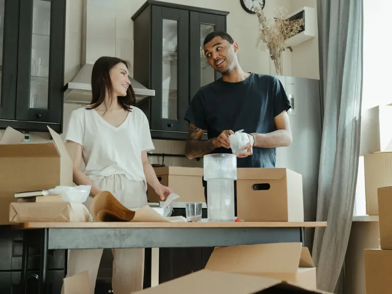 Smiling couple unpacking boxes in their new home kitchen, ready for a fresh start.