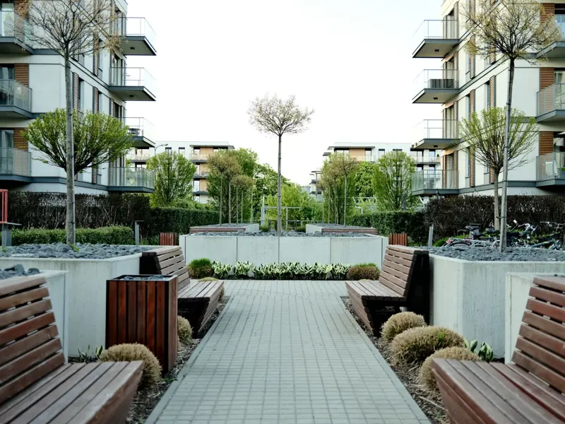 Charming contemporary garden walkway flanked by benches in a vibrant urban setting, offering a serene escape.