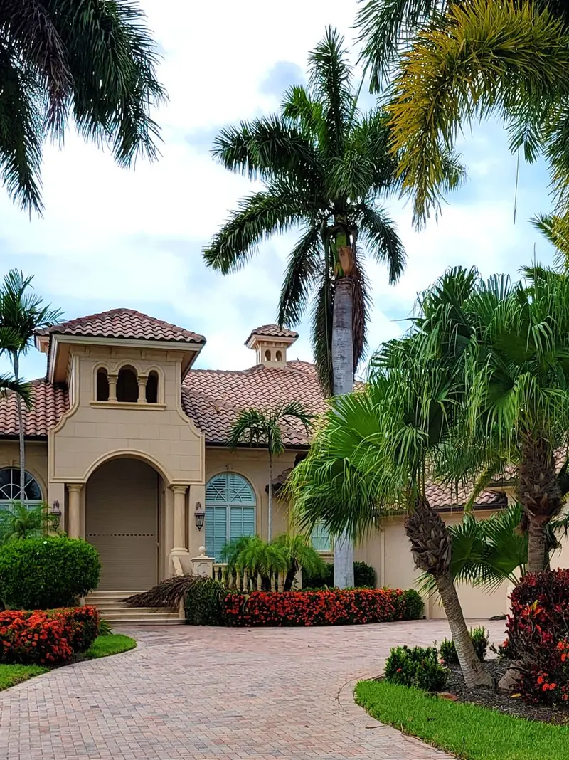 Elegant mansion with lush palm trees and landscaped garden, perfect for luxury living.