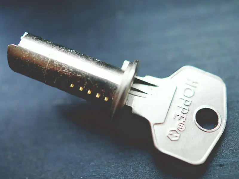 Detailed close-up image of a metallic key with lock cylinder on a dark surface, highlighting intricate details.