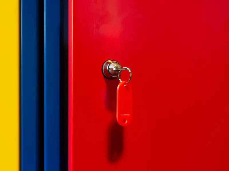 A vibrant image of a red locker door with a key in the lock, featuring bold primary colors.