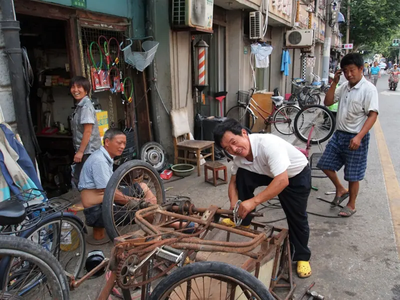 Local bicycle repair in Shanghai's bustling street, capturing everyday life.