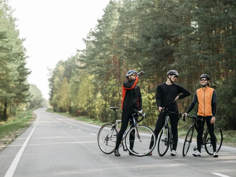 Three cyclists pause for a break in a serene forest setting, enjoying the outdoors.