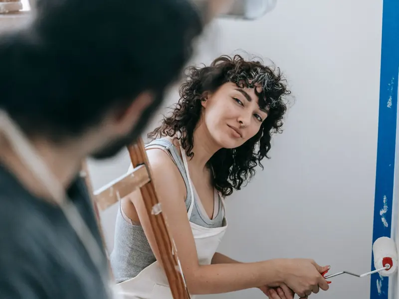 A couple enjoying painting their new home together, creating a vibrant and cozy space.