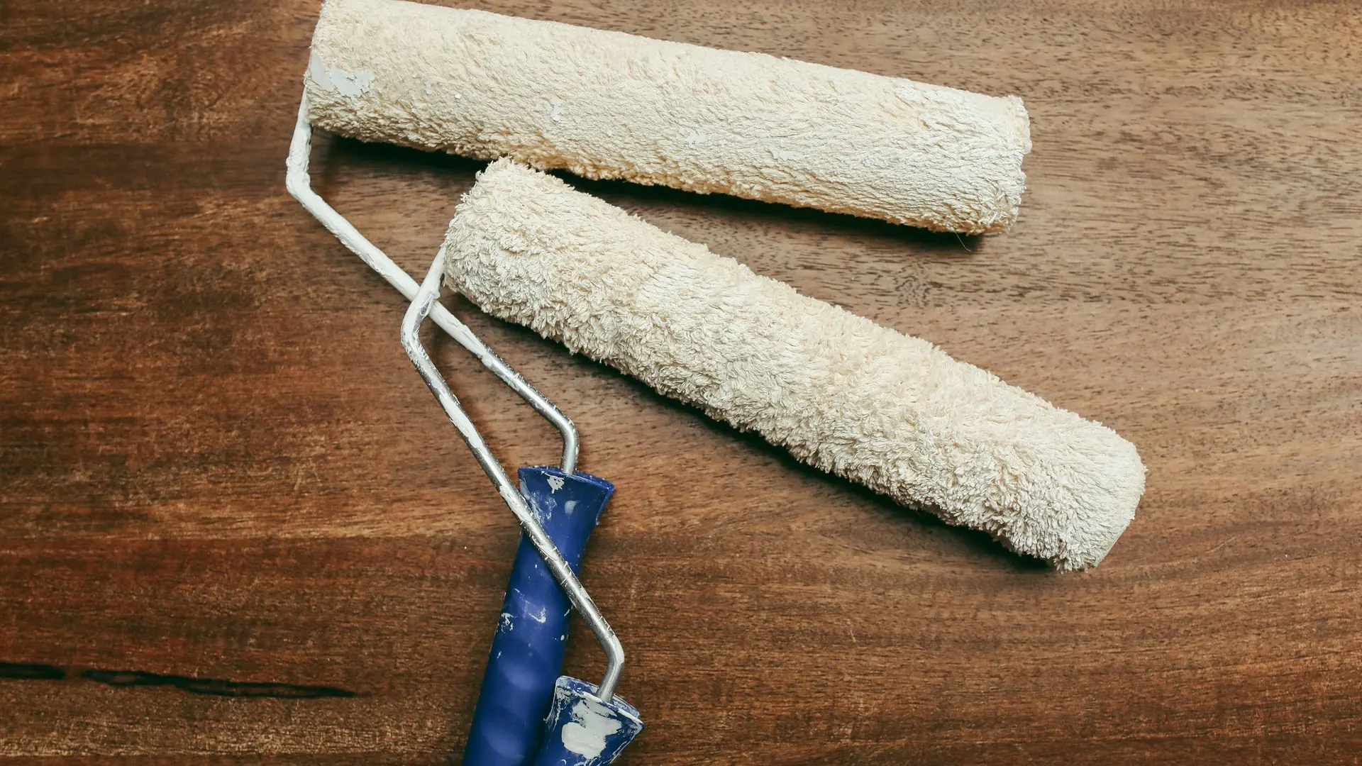 Two paint rollers over a wooden surface, perfect for home renovation concepts.