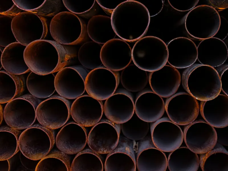 Close-up view of stacked rusty industrial pipes, showcasing their texture and corrosion.