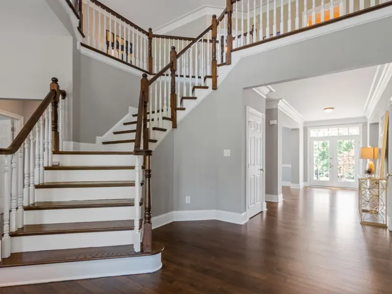 Bright and spacious entryway with wooden staircase and natural lighting.