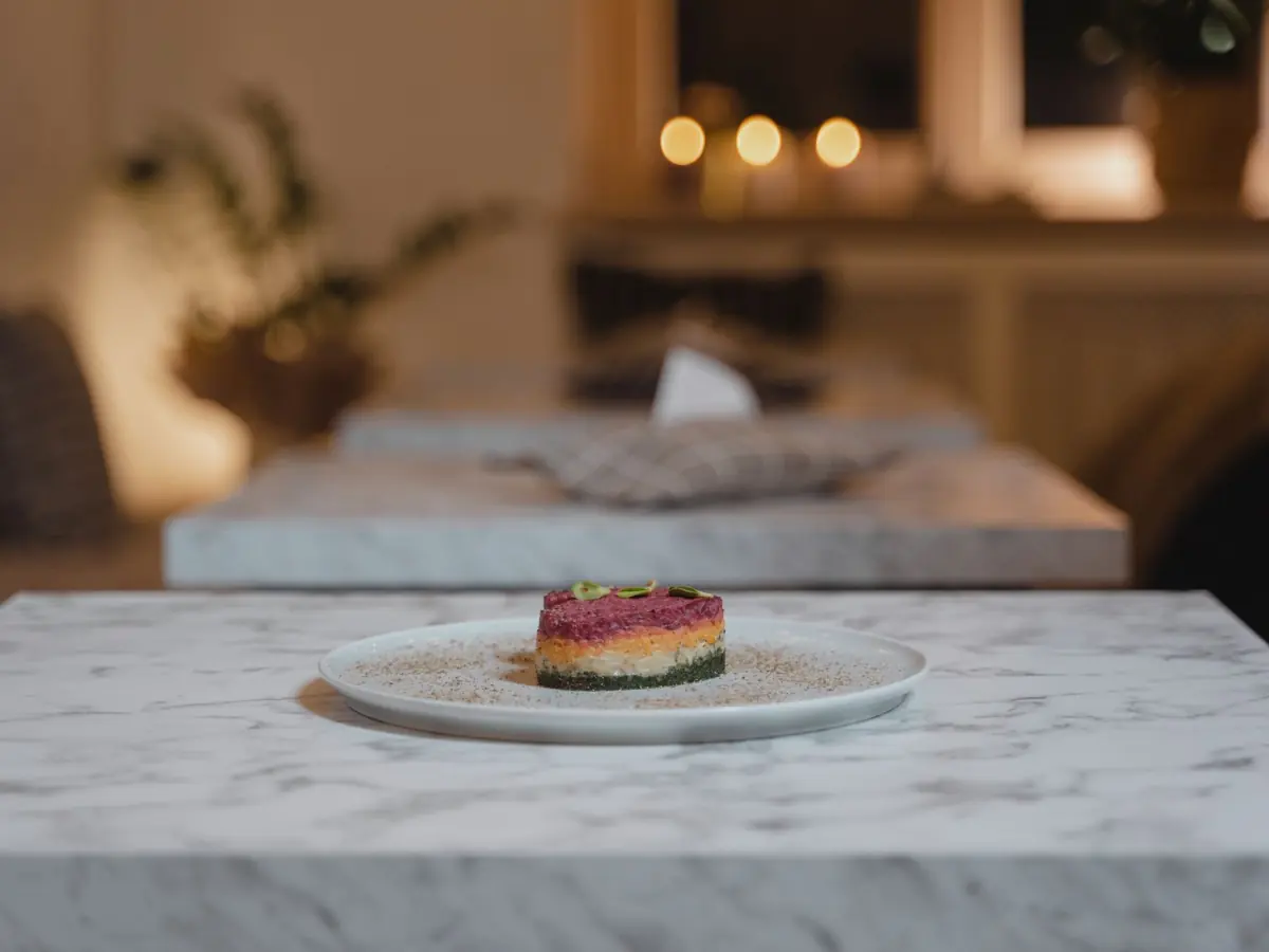A beautifully presented gourmet dish on a marble table in a cozy restaurant setting with warm lighting.