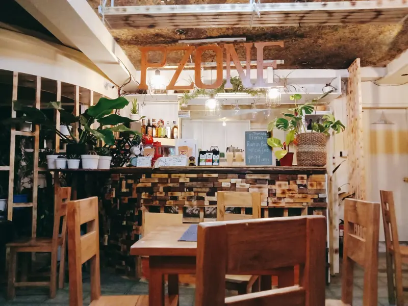 Warm and inviting indoor bar setup with wooden furniture, lush plants, and rustic design elements.
