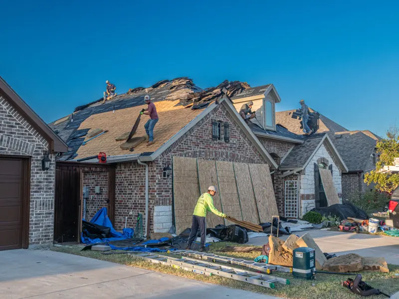 Workers engage in roof replacement on a brick house in Fort Worth, Texas.