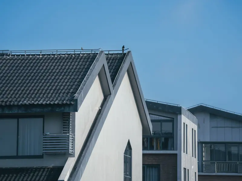 Modern residential buildings with unique architectural rooftops under a clear blue sky.