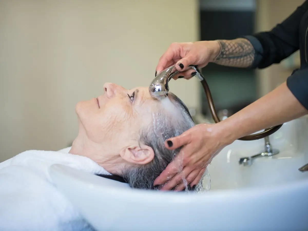 Elderly woman receiving a relaxing hair wash in a salon setting.