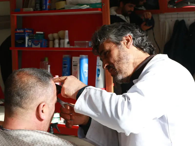 A barber focuses on cutting a customer's hair in a well-equipped barbershop.