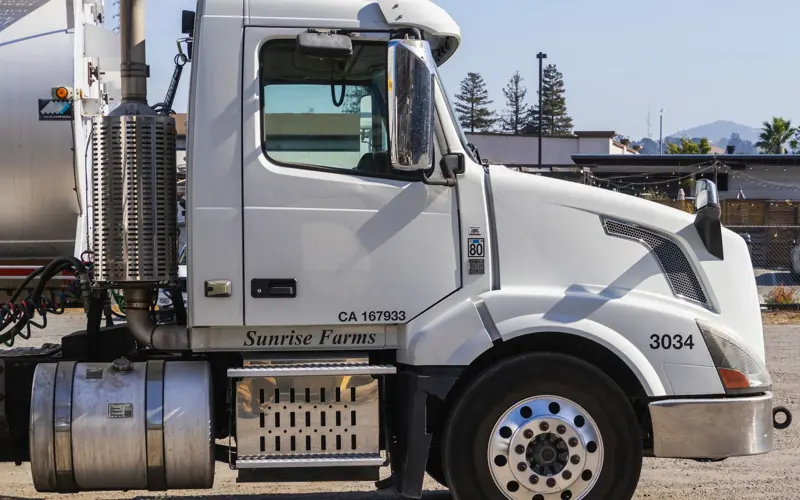 Side view of a white semi-trailer truck parked outdoors in an industrial area.