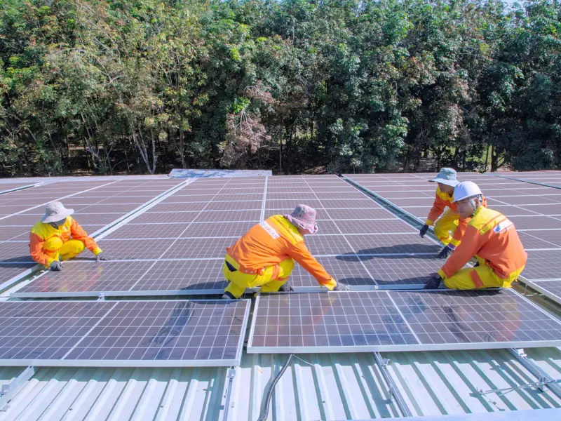 Team of workers installing solar panels on a sunny day, promoting renewable energy and sustainability.