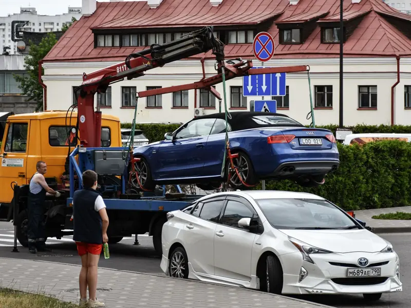 Towing a blue Audi convertible in a bustling city street.
